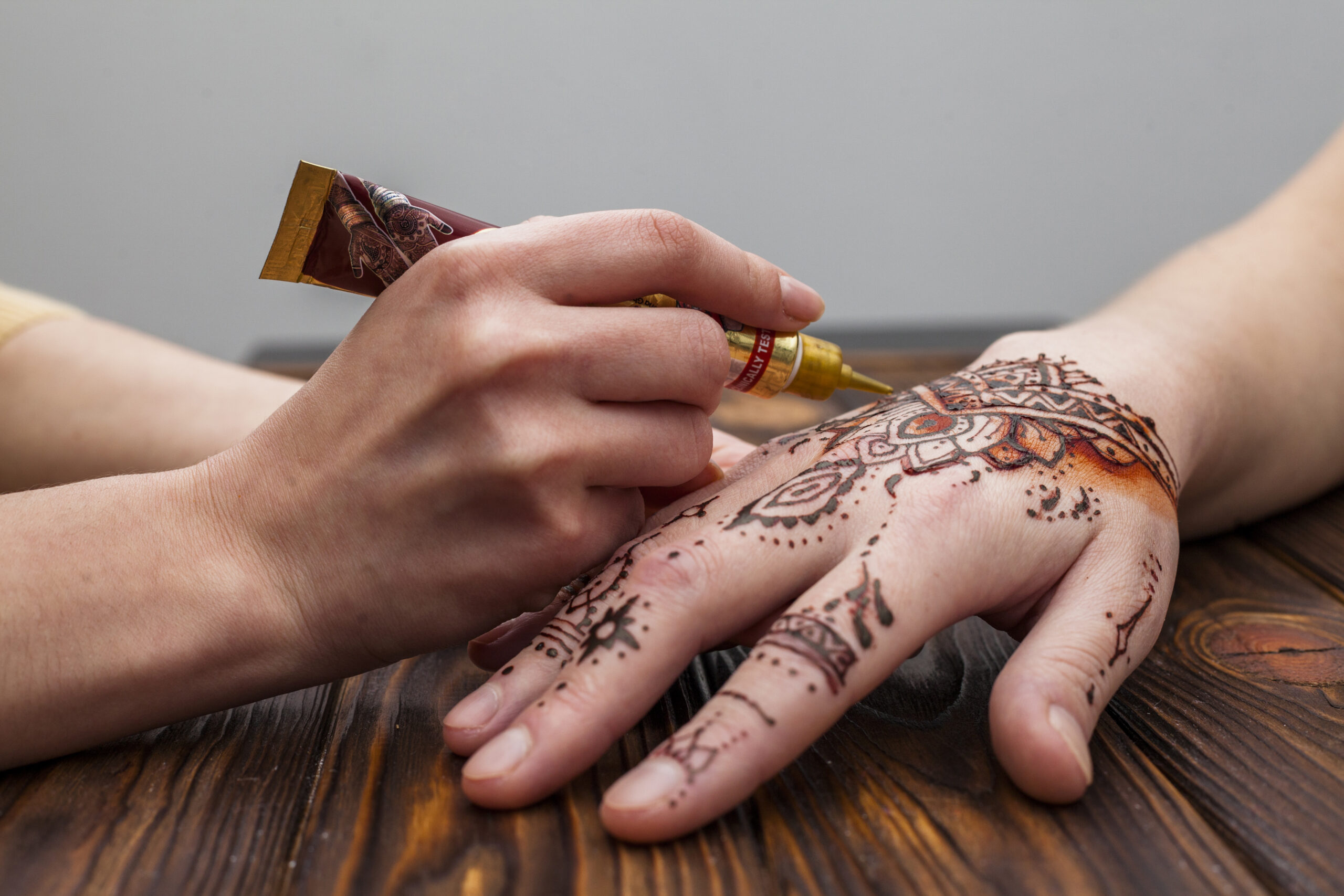 artist-making-mehndi-womans-hand-table